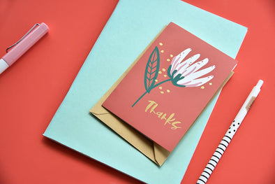 hand drawn white tulip thank you card on burnt orange card with teal and orange backdrop
